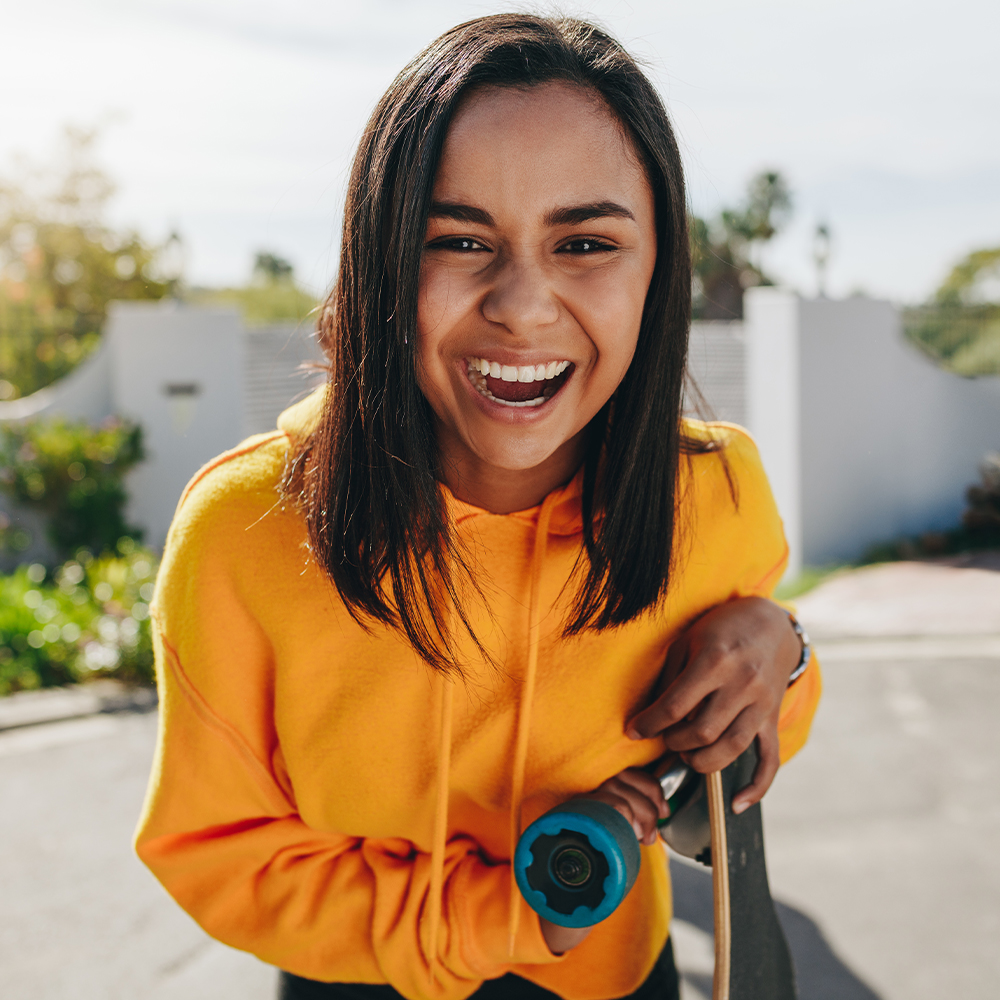woman smiling at the camera while wearing a bright yellow sweatshirt